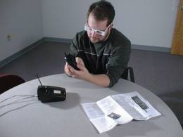 A test subject wearing low vision simulation glasses attempts to dial a telephone.